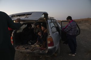 File - Afghan migrants get in a car near the village of Islam Qala, on Wednesday, Nov. 24, 2021 to drive near the Afghanistan-Iran border in their effort to cross Iran. Afghans are streaming across the border into Iran, driven by desperation after the near collapse of their country's economy following the Taliban's takeover in mid-August. In the past three months, more than 300,000 people have crossed illegally into Iran, according to the Norwegian Refugee Council, and more are coming at the rate of 4,000 to 5,000 a day.