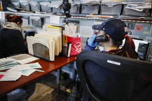 Employee Gina Hansen wears protective gloves due to COVID-19 concerns at Daniel J. Schaefer Funeral Home that is handling overflow of clients stemming from pandemic deaths, Thursday, April 2, 2020, in the Brooklyn borough of New York