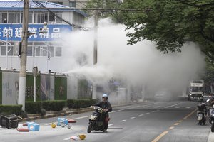 A rider past by helmets and plastics thrown out by workers at a construction site in Shanghai on Friday, May 27, 2022