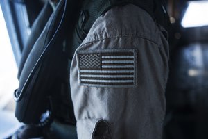 A CH-53E super stallion crew chief assigned to Marine Heavy Helicopter Squadron 463 "Pegasus," brandishes a coyote American flag patch on his uniform during a flight around Oahu, Hawaii, Sept. 23, 2014