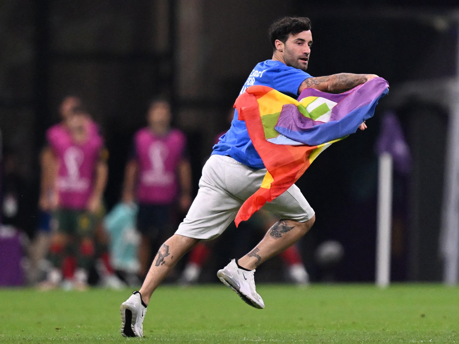 A man invades the pitch holding a LGBT flag as he wears a tshirt reading Respect for Iranian woman during the Qatar 2022...