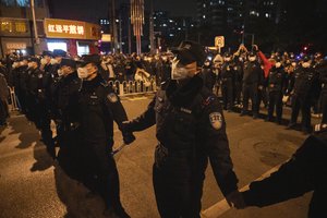 Chinese policemen form a line to stop protesters marching in Beijing, Sunday, Nov. 27, 2022