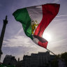 People wave a pre-Islamic revolution Iranian flag in London. As protests go global, so does Iranian repression. 