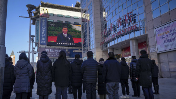 People watch a live broadcast of the memorial service for late former Chinese President Jiang Zemin. 