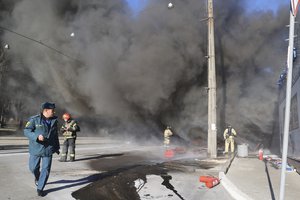 Firefighters work at the scene of a burning vehicle and a shop damaged in shelling by Ukrainian forces in a street in Donetsk, the capital of Russian-controlled Donetsk region, eastern Ukraine, Tuesday, Dec. 6, 2022