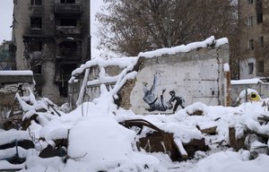 An artwork made by British street artist Banksy is seen on a building destroyed by the Russian army, among debris covered by snow in Borodyanka, Kyiv region, Ukraine, Tuesday, Dec. 6, 2022.