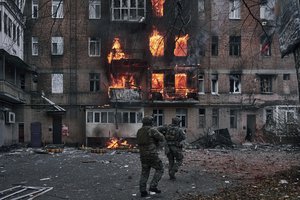 Ukrainian soldiers run to help people in an apartment house in fire after the Russian shelling in Bakhmut, Donetsk region, Ukraine, Wednesday, Dec. 7, 2022.