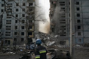 A firefighter looks at a part of a wall falling from the residential building that was heavily damaged after a Russian attack in Zaporizhzhia, Ukraine, Sunday, Oct. 9, 2022