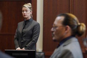 Actors Amber Heard and Johnny Depp watch as the jury leaves the courtroom for a lunch break at the Fairfax County Circuit Courthouse in Fairfax, Va., Monday, May 16, 2022