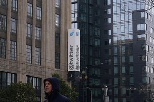 A pedestrian walks below a Twitter logo hanging outside the company's offices in San Francisco, Monday, Dec. 19, 2022