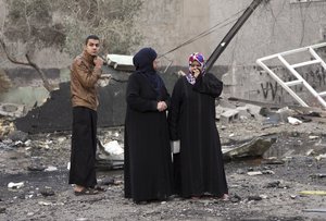 Civilians gather at the scene in the aftermath of a car bomb explosion in commercial area of New Baghdad, Iraq, Tuesday, Jan 12, 2016.