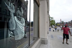 Tushar Gupta, of Boston, right, uses a mobile device near a window featuring a likeness, left, of chef and social media star known as Salt Bae outside the Nusr-Et Boston restaurant, Tuesday, Sept. 29, 2020, in Boston.