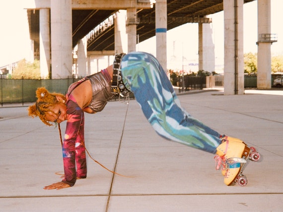 A person in brightly colored clothing perreando in their skates.