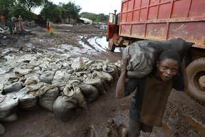 A young man carries wet Cobalt on his back at the Shinkolobwe Cobalt mine