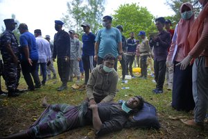 An ethnic Rohingya man lies on the ground as he waits for medical treatment after landing on Indra Patra beach in Ladong village, Aceh province, Indonesia, Sunday, Dec. 25, 2022