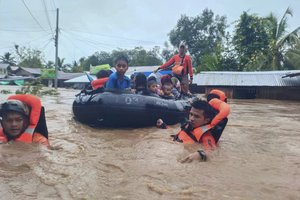 In this photo made available by the Philippine Coast Guard, rescuers use rubber rafts to pull residents out of flooded areas in the aftermath of Tropical Storm Nalgae in Parang, Maguindanao province, southern Philippines, on March 28. October 2022