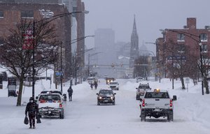 People and vehicles move about Main St. in Buffalo, N.Y., Monday, Dec. 26, 2022, after a massive snow storm blanketed the city