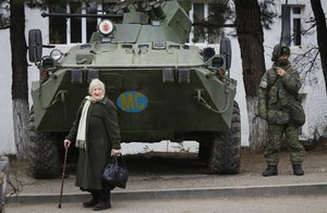 File - An elderly Ethnic Armenian woman stands next to a Russian peacekeeper's APC in Berdzor in the separatist region of Nagorno-Karabakh, Thursday, Nov. 26, 2020.