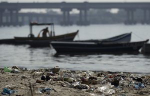 In this photo taken on Friday, June 15, 2012, a fisherman takes his boat onto a trash-ridden beach on Guanabara Bay near the international airport in Rio de Janeiro, Brazil.