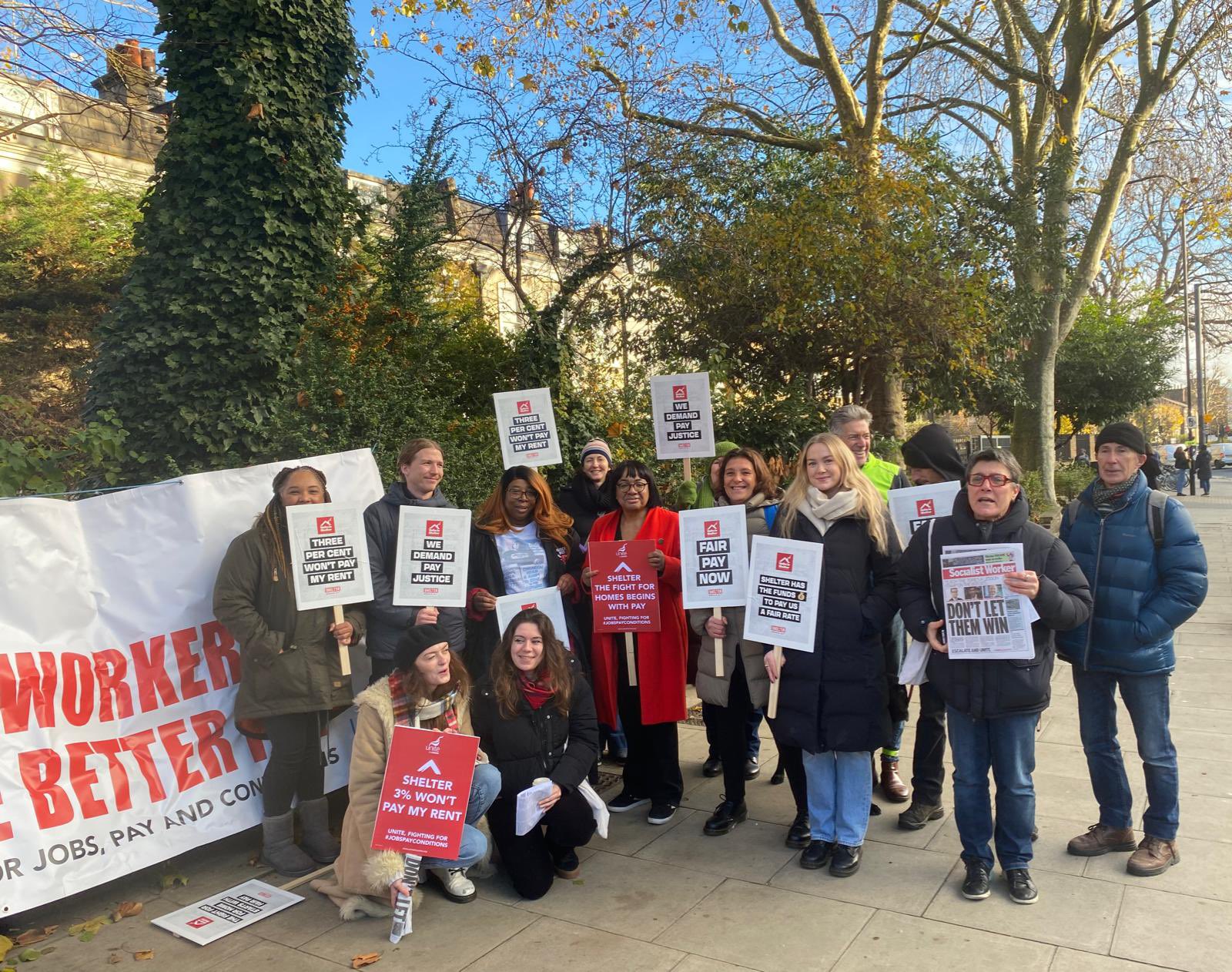 Dianne Abbott MP stands with Shelter staff in Hackney. Signs say “fair pay now?