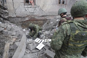 Investigators inspect a site of an apartment building after shelling by Ukrainian forces in Makiivka, Donetsk People's Republic, eastern Ukraine, Friday, Nov. 4, 2022