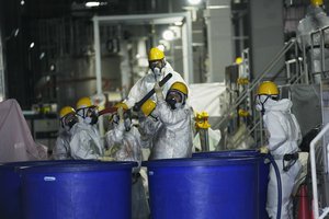 File - Men in hazmat suits work inside a facility with equipment to remove radioactive materials from contaminated water at the Fukushima Daiichi nuclear power plant, run by Tokyo Electric Power Company Holdings (TEPCO), in Okuma town, northeastern Japan, Thursday, March 3, 2022.