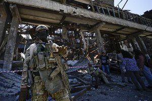 A Russian soldier speaks to foreign journalists in front of the ruined Metallurgical Combine Azovstal, in Mariupol, on the territory which is under the Government of the Donetsk People's Republic control, eastern Ukraine, Monday, June 13, 2022