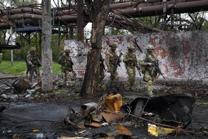 FILE - Russian troops walk in a destroyed part of the Illich Iron & Steel Works Metallurgical Plant in Mariupol, in territory under the government of the Donetsk People's Republic, eastern Ukraine, Wednesday, May 18, 2022.