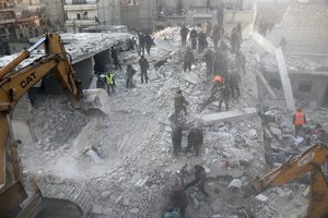 In this photo provided by Kurdish-run Hawar News Agency, civil defense workers and civilians work on the rubble of a destroyed building in the Sheikh Maksoud neighborhood in Aleppo, Syria, Sunday, Jan. 22, 2023. The building collapsed in Aleppo early Sunday, killing at least 10 people, Syrian state media reported. (Hawar News Agency via AP)