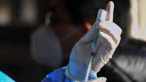 In this photo released by Xinhua News Agency, a medical worker prepares to administer a second booster dose of COVID-19 vaccine for a resident, at a temporary vaccination site in Beijing, Saturday, Dec. 17, 2022. (Ren Chao/Xinhua via AP) 