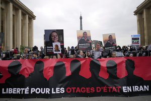 People hold portraits of French detainees in Iran Cecile Kohler, left, and Benjamin Briere during a protest in Paris, Saturday, Jan. 28, 2023.