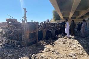 People look at the burnt wreckage of a bus accident in Bela, an area of Lasbela district of Balochistan province, Pakistan, Sunday, Jan. 29, 2023.