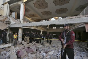 Police officers examine the site of Monday's suicide bombing after authorities finished the rescue operation, in Peshawar, Pakistan, Tuesday, Jan. 31, 2023. A suicide bombing that struck inside a mosque at a police and government compound in northwest Pakistan reflects "security lapses," current and former officials said as the death toll from the devastating blast climbed to 100 on Tuesday.