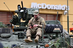 US Army soldier with camouflages and sitting on top of a tank