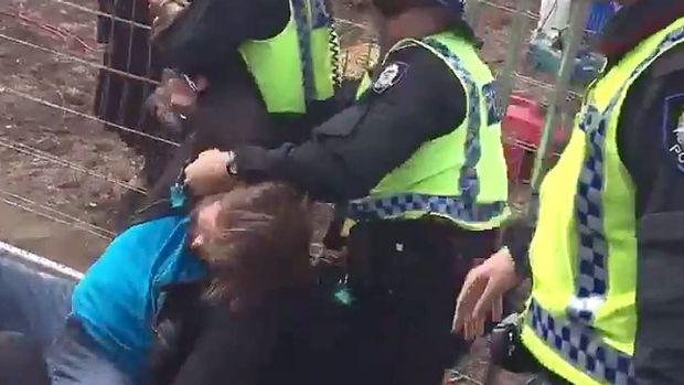 A protesters is hand-cuffed by police after the fences guarding the site were pushed down