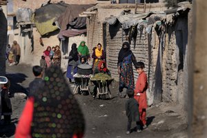 Women and children walk through a muddy alley in a poor neighborhood in Kabul, Afghanistan, Wednesday, Feb. 16, 2022.