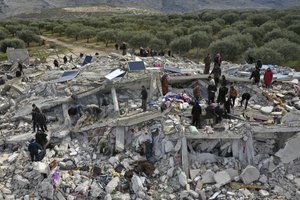 Civil defense workers and residents search through the rubble of collapsed buildings in the town of Harem near the Turkish border, Idlib province, Syria, Monday, Feb. 6, 2023. A powerful earthquake has caused significant damage in southeast Turkey and Syria and many casualties are feared. Damage was reported across several Turkish provinces, and rescue teams were being sent from around the country.