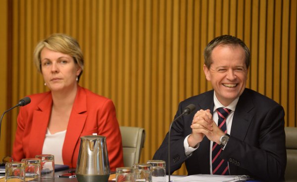 Tanya Plibersek, wearing a serious expression, is seated next to Bill Shorten, who is smiling