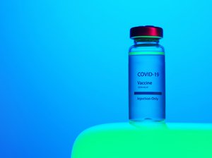 A close-up view of a Covid-19 vaccine vial on blue background