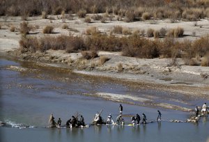 File - Afghans try to repair a dam on a river as seen from the British forces forward operating base Sterga II at Helmand province in southern Afghanistan, Dec. 16, 2013.