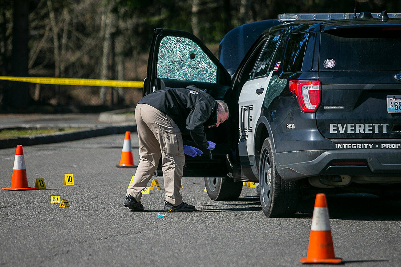 A crime scene investigator surveys the area around a police car that was involved in a shooting early Wednesday morning along Highway 99 that left one person dead. (Olivia Vanni / The Herald).