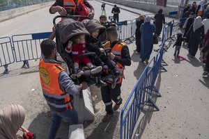 Paramedic volunteers help a Palestinian woman with her children while she heads to cross from the West Bank into Jerusalem, for prayers during the Muslim holy month of Ramadan at the Al Aqsa mosque compound, at the Qalandia Israeli army checkpoint, near Ramallah, Friday, March 24, 2023. The Muslim holy month of Ramadan begins at sundown. The faithful are preparing for a month of dawn-to-dusk fasting intended to bring them closer to God and to remind them of the suffering of those less fortunate.