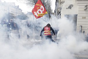 A unionist kicks a tear gas canister during a protest Thursday, April 6, 2023 in Nantes, western France