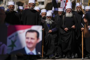 Druze men carry Syrian flags and a picture of Syrian President Bashar Assad during a rally marking Syria's Independence Day, in the Druze village of Majdal Shams in theIsraeli-controlled Golan Heights, on the border with Monday, April 17, 2023.