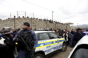 Curious onlookers behind a police cordon, where ten people from the same family were shot dead Friday, April 21, 2023.