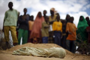 FILE - In this Saturday Aug. 6, 2011 file photo, the shrouded body of 12-month-old Liin Muhumed Surow, who died of malnutrition 25 days after reaching the camp according to her father Mumumed, lies before burial at UNHCR's Ifo Extension camp, near Dadaab in Kenya close to the Somali border.