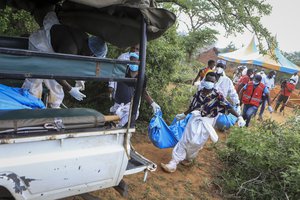 Police and local residents load the exhumed bodies of victims of a religious cult into the back of a truck in the village of Shakahola, near the coastal city of Malindi, in southeastern Kenya Sunday, April 23, 2023