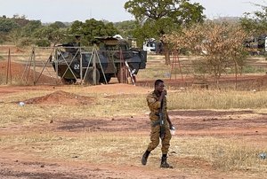 A Burkinabe soldier walks past a French Armoured Personnel Carrier part of a French military convoy heading to Niger, stopped by protesters in Kaya, Burkina Faso, Saturday Nov. 20, 2021