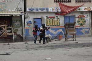 Police officers take cover during an anti-gang operation in the Portail neighborhood of Port-au-Prince, Haiti, Tuesday, April 25, 2023, a day after a mob in the Haitian capital pulled 13 suspected gang members from police custody at a traffic stop and beat and burned them to death with gasoline-soaked tires.