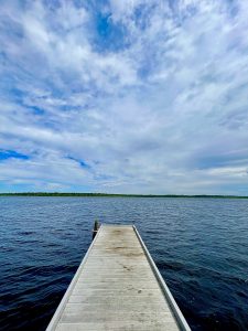 Steel dock stretching into a lake on a sunny day with blue skies